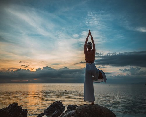 person stretching at sunrise by the sea